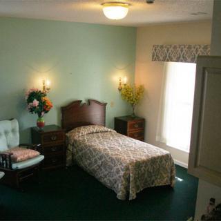 A cozy bedroom with a single bed, a chair, and warm lighting.