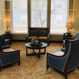 A cozy seating area with comfortable chairs, a sofa, and warm lighting.