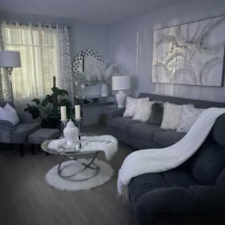 A stylish and serene living room featuring a modern grey sofa, elegant decor, and soft lighting.
