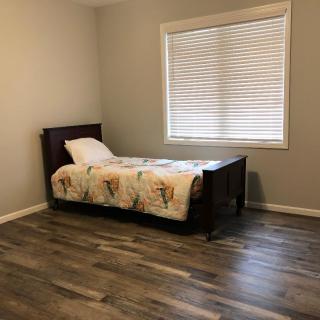 A minimalist bedroom with a single bed and hardwood flooring.