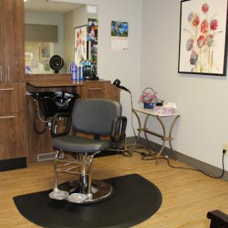 A modern hair salon featuring a stylish styling chair and decorative wall art.