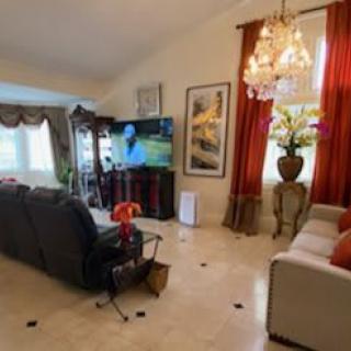 A cozy living room with a sofa, television, and elegant chandelier.