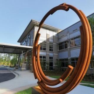 A modern metal sculpture in front of a contemporary building.