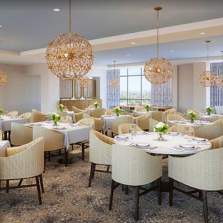 A modern and elegant dining room with beautifully set tables, upholstered chairs, and stunning chandeliers.