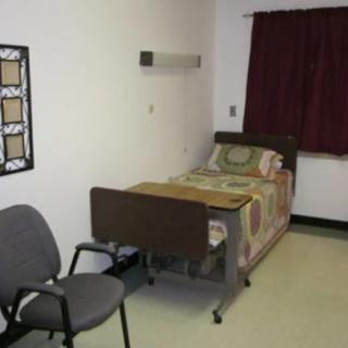 A simple hospital room with a single bed and chair.