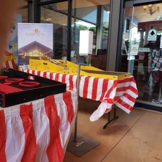 A carnival-style game setup outside with striped tablecloths and a colorful backdrop.