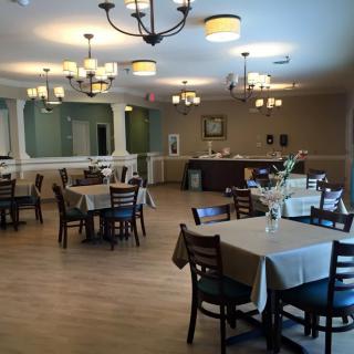 A cozy restaurant dining area with neatly arranged tables and chairs, illuminated by chandeliers.