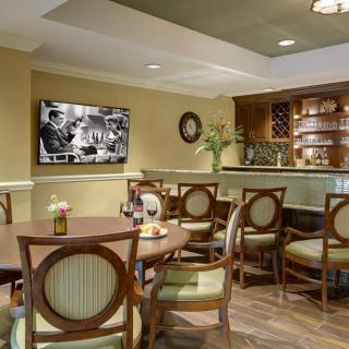 A cozy dining area with elegant seating and a small bar, featuring a television on the wall.