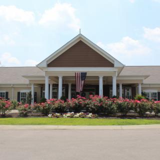 A suburban building entrance with landscaped flowers and a flagpole.