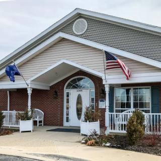 A building with a front entrance displaying two flags on poles.
