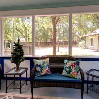 A cozy sunroom with a view of nature, featuring comfortable seating and decorative elements.