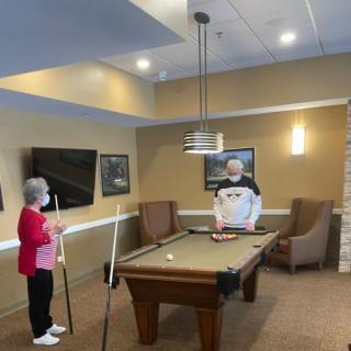 Two people enjoying a game of billiards in a cozy game room.