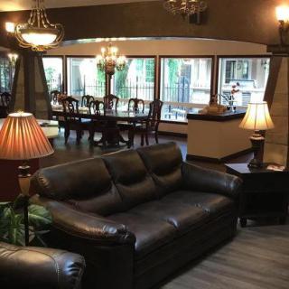 A cozy living and dining space featuring a leather sofa, warm lighting, and a wooden dining set.
