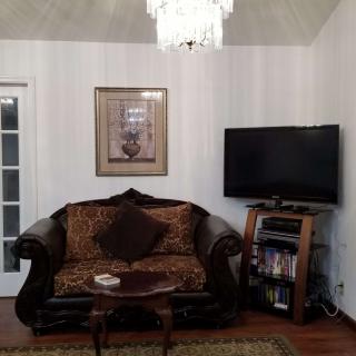 A cozy living room with a sofa, chandelier, and television.
