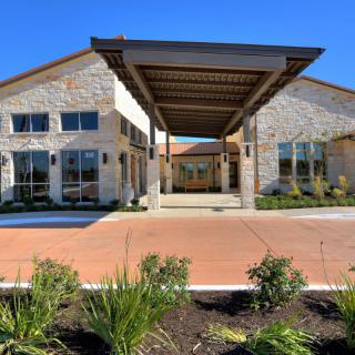 A modern building with a landscaped entrance and stone facade.