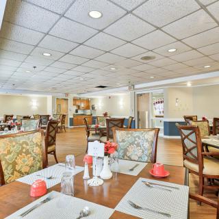 The image shows an empty restaurant dining room with neatly set tables and chairs.