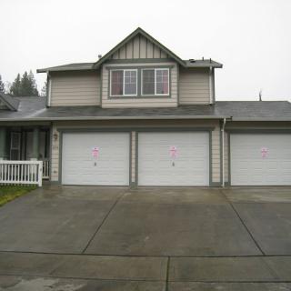 A two-story house with a three-car garage and a wide driveway.