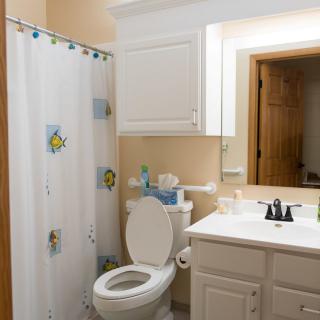 A clean and organized bathroom with a shower curtain and white cabinetry.