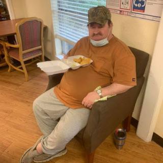 A man sitting comfortably in a chair, enjoying his meal.