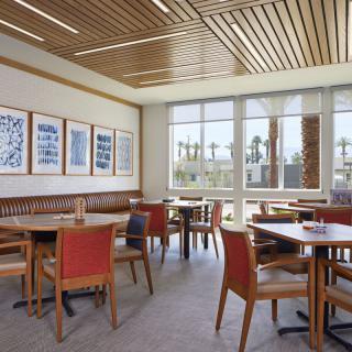 A modern restaurant dining area with wooden furnishings and large windows.