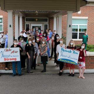 A group of people gathered outside a building, holding signs to show support and solidarity.