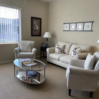 A cozy living room with a comfortable sofa, two armchairs, and a glass coffee table, all arranged around decorative elements.