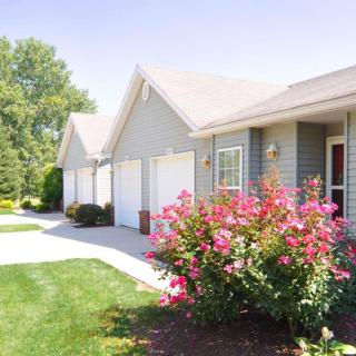 A row of suburban houses with a neatly landscaped garden and driveway.