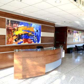 A modern reception area featuring a vibrant artwork and sleek wooden furniture.