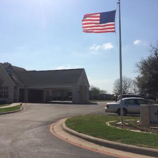 A vibrant American flag waving on a flagpole outside a building under a clear blue sky.