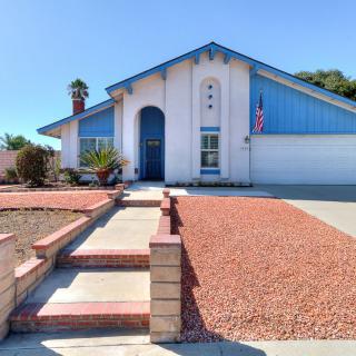 A suburban house with blue trim and a landscaped front yard.