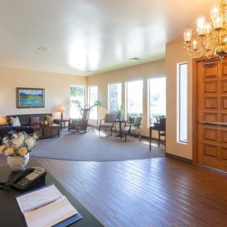 A spacious living room with wooden flooring, natural lighting, and elegant furnishings.