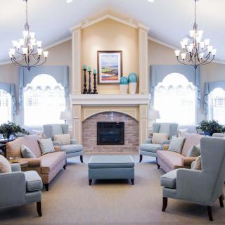A cozy living room featuring a central fireplace, multiple sofas, and elegant chandeliers.