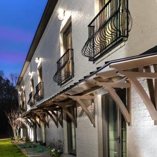 A modern house exterior illuminated at dusk with stylish balconies and wooden overhangs.