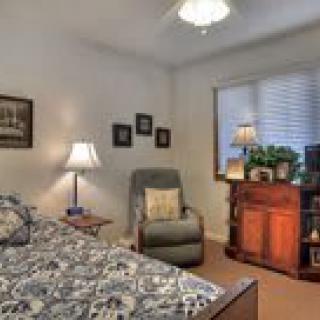 Cozy bedroom with patterned bedding, a comfy chair, and warm lighting.