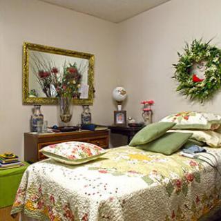 A cozy bedroom with a decorative wreath and a floral quilt on the bed.