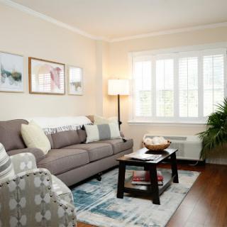 A cozy living room featuring a comfortable couch, artistic wall decor, and natural light from the windows.