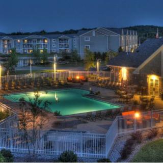 A serene nighttime view of a resort with a well-lit swimming pool and surrounding buildings.