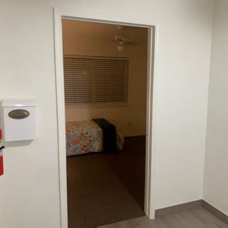 A view through a doorway into a bedroom with a bed and window.