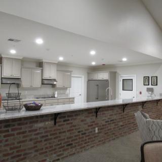A modern kitchen with brick accent and counter seating, featuring recessed lighting.