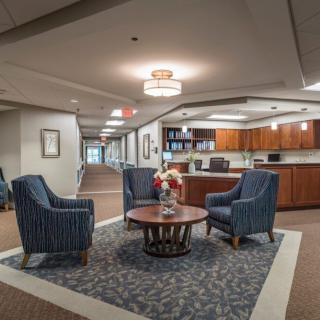 A modern lobby seating area with blue armchairs and a central table, featuring elegant lighting.
