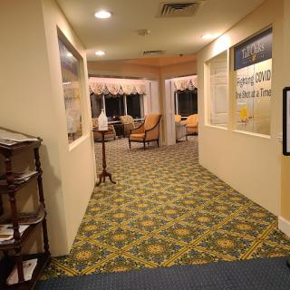 A cozy hallway leading to a seating area, featuring patterned carpet and warm lighting.