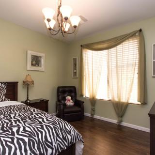 A cozy bedroom with zebra-patterned bedding, a black chair, and a chandelier.