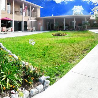 A sunny day view of a building with a well-maintained lawn and garden.