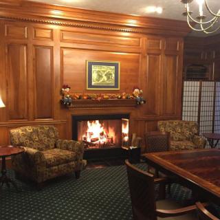 A cozy living room with a warm fireplace and elegant wood paneling.