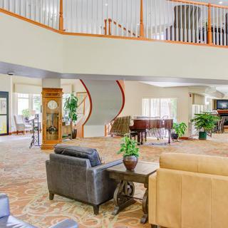 A spacious lounge area with elegant furniture, a piano, and a spiral staircase.