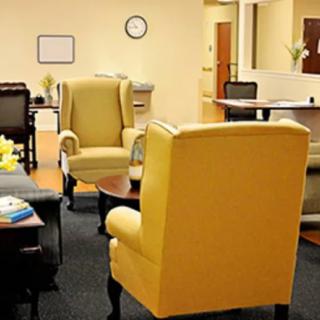 A cozy office waiting area with yellow chairs and a central table.