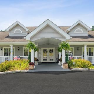 A symmetrical front view of a residential building with a porch and surrounding landscaping.
