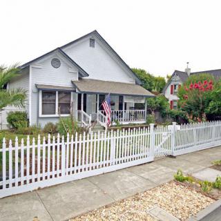 A charming suburban house with a white picket fence and a well-kept front yard.