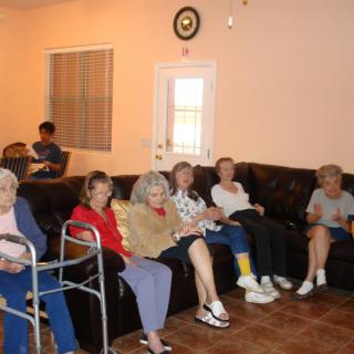 A group of seniors seated in a living room setting.