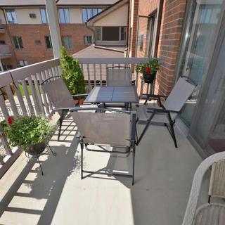 A sunny balcony with outdoor furniture and potted plants.